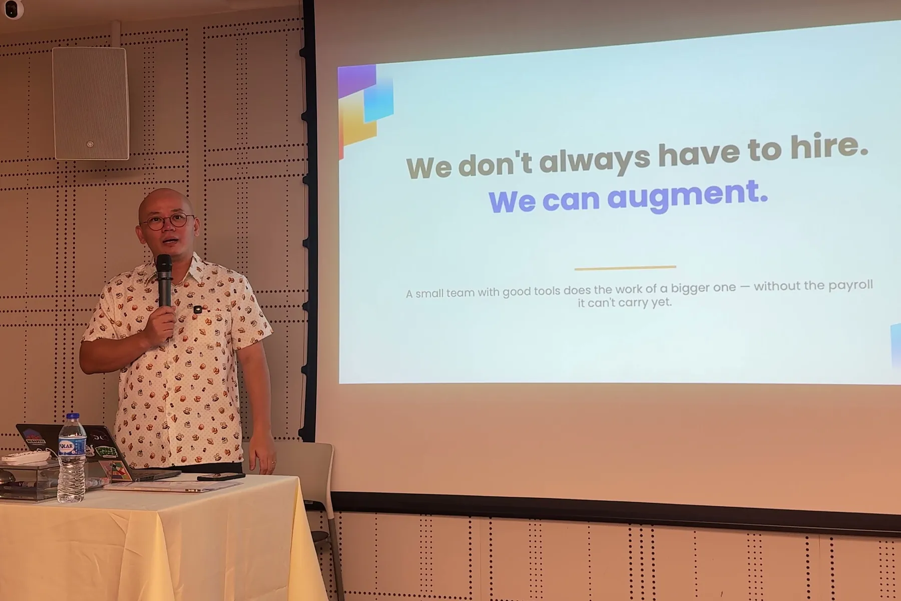Haojun See speaking at Towkay Talks Series 5 beside his slide, "We don't always have to hire. We can augment."