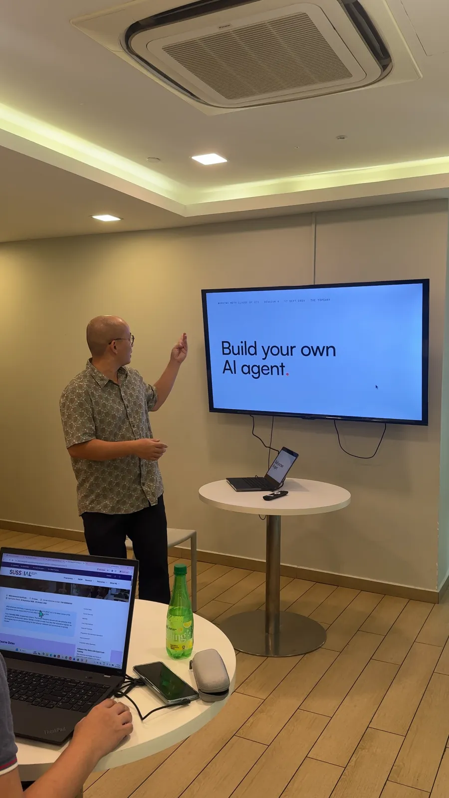 Haojun See pointing to the opening slide, "Build your own AI agent", at Working with Claude by OTG #4